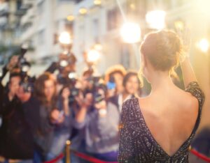 Celebrity on red carpet with photographers in background.