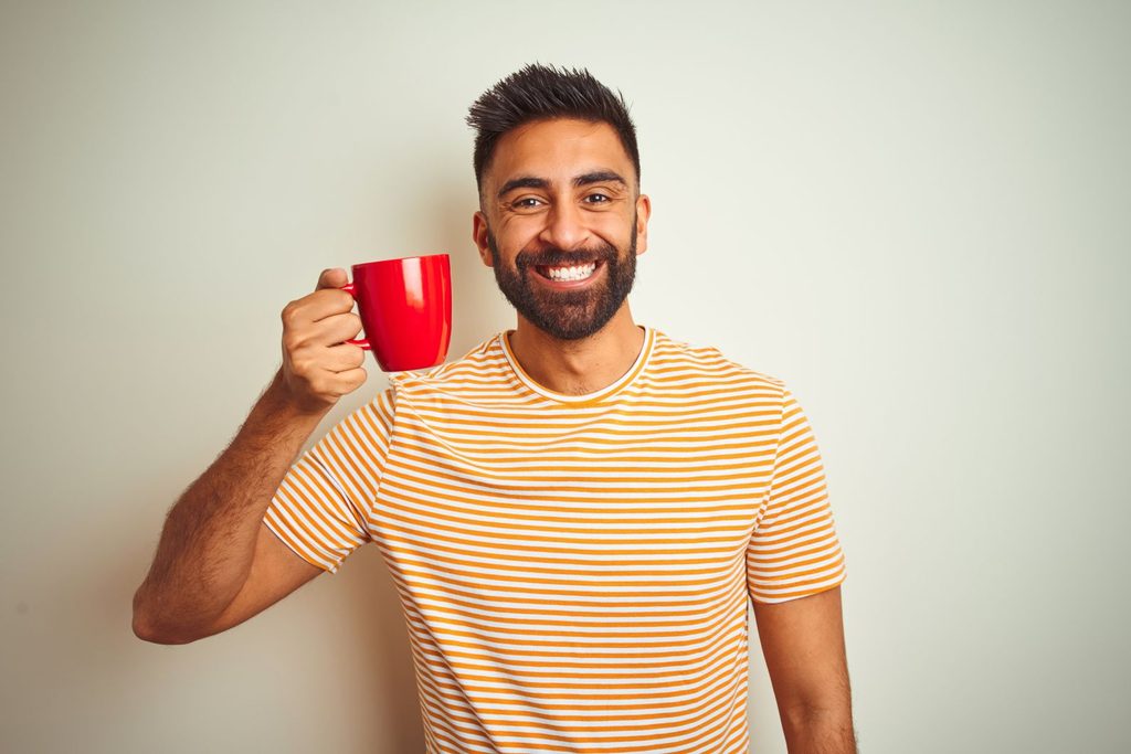 A smiling man holding a mug